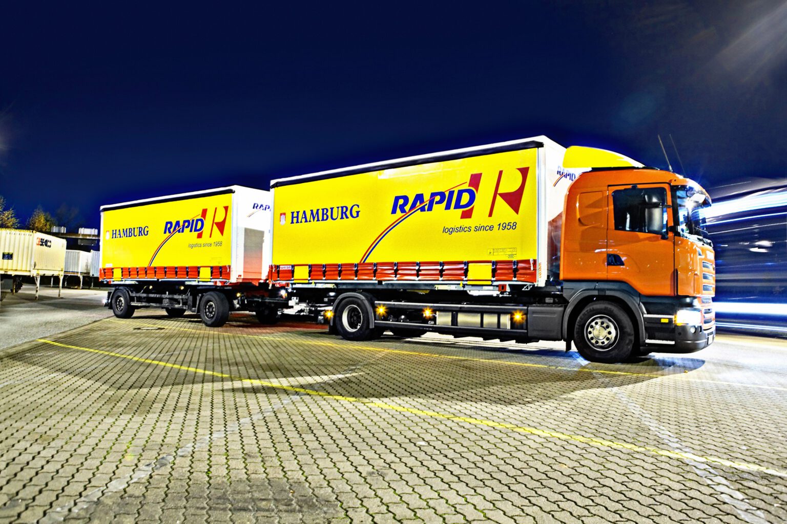 Gelb-oranger Rapid-Lastzug mit Aufschrift Hamburg und logistics since 1958, 2015